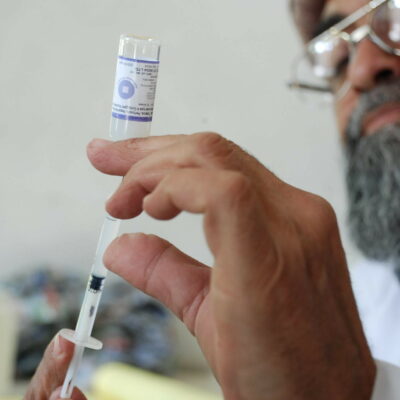 A man draws medication into the syringe he holds in the foreground.