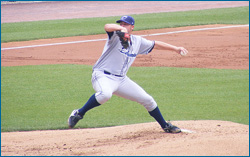 A pitcher pulls his arm back and prepares to throw a baseball.
