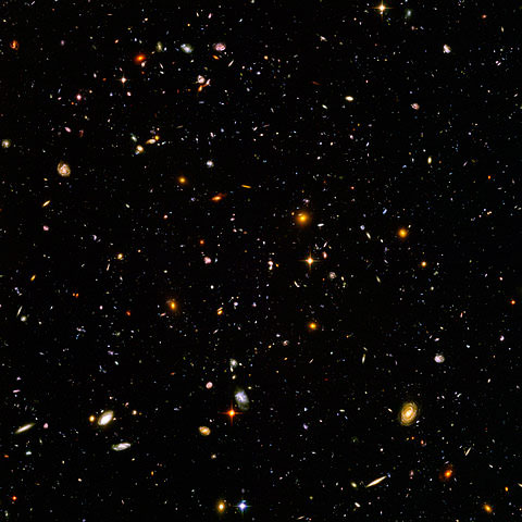 Black field filled with a scattering of small shapes and dots of different colors